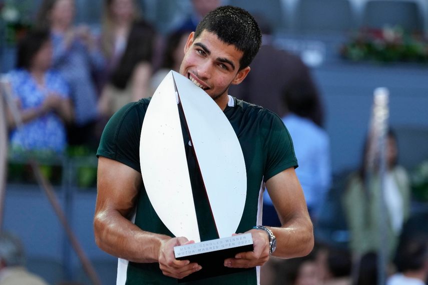 Carlos Alcaraz muerde el trofeo de campeón tras vencer a Alexander Zverev en la final del Abierto de Madrid, el domingo 8 de mayo de 2022.&nbsp;