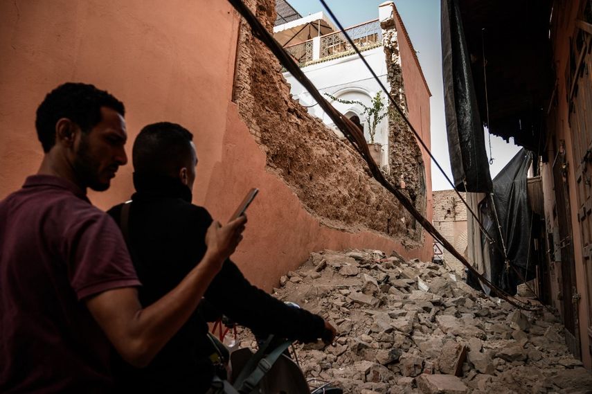 Un hombre que viaja en una motocicleta revisa su teléfono como en una calle bloqueada por el estruendo de un riad dañado por el terremoto en un barrio del casco antiguo de Marrakech el 10 de septiembre de 2023.