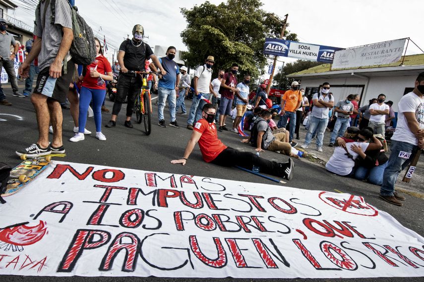 La gente se manifiesta junto a un cartel que dice No m&aacute;s impuestos a los pobres, haz que los ricos paguen, contra la moci&oacute;n del gobierno de aumentar los impuestos para llegar a un acuerdo crediticio con el Fondo Monetario Internacional (FMI), frente a la casa presidencial en San Jos&eacute;, el 12 de octubre de 2020.
