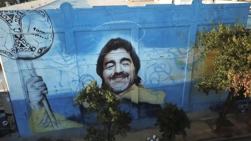 Colgado de una grúa, el artista pinta el rostro del capitán del equipo campeón del mundo en México-1986, fallecido el 25 de noviembre a los 60 años.