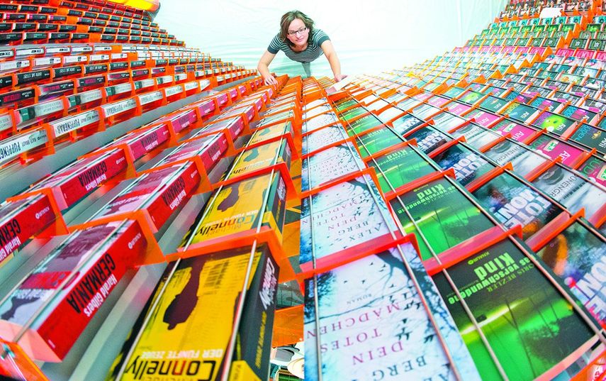 Una empleada coloca libros en un puesto de ventas, horas antes de la apertura de la cita literaria en la ciudad alemana. (EFE)