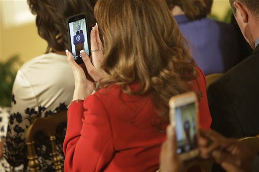 Dos personas del público usan sus teléfonos para grabar o tomar fotos del presidente Barack Obama en la Casa Blanca, el jueves 12 de febrero de 2015, en Washington. (Foto AP)