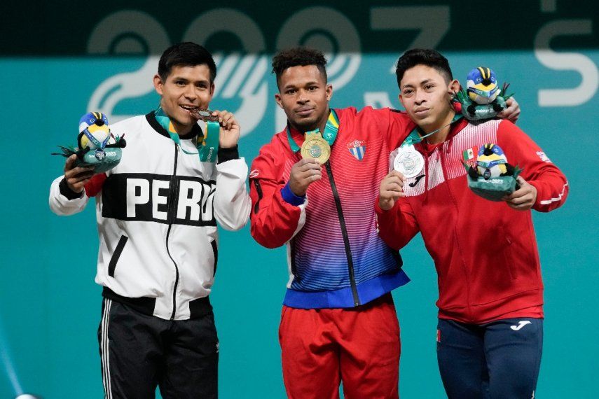 De izquierda a derecha, el peruano Luis Bardales, por Cuba, Arley Calderón y el mexicano Víctor Guemez posan en el podio de los 61 kilogramos del levantamiento de pesas de los Juegos Panamericanos en Santiago, Chile, el sábado 21 de octubre de 2023.&nbsp;