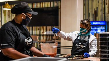 Cumpliendo con todos los protocolos de seguridad, la chef dominicana Dayanny de la Cruz (der.) sirve raciones para el Programa de ayuda alimentaria de los Dolphins de Miami. 