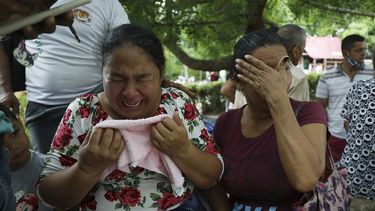 Mujeres lloran mientras explican que tres de sus familiares fueron asesinados el día anterior en El Ripial, estado Apure, Venezuela, luego de cruzar el río hacia Arauquita, Colombia, el viernes 26 de marzo de 2021.