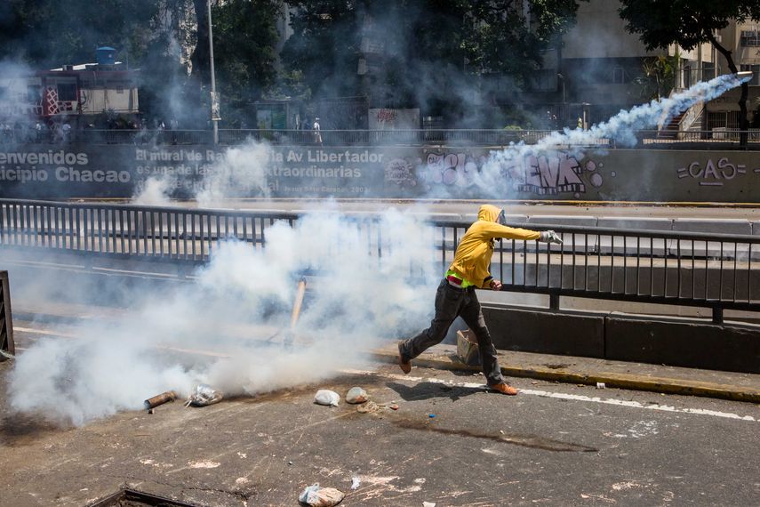 Un manifestantes devuelve una bombas lacrimógena a la Policía Nacional Bolivariana durante la reyerta de este sábado en la avenida Libertador.&nbsp;