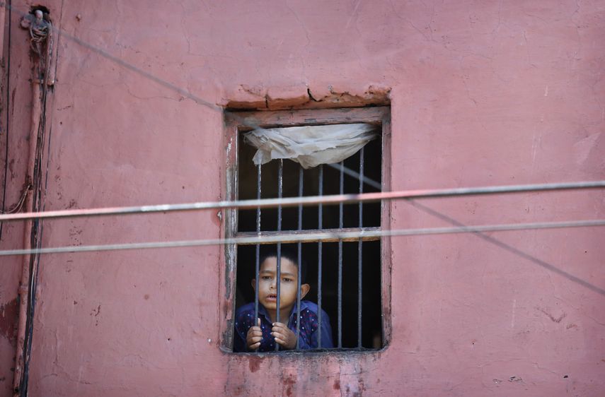 Un niño mira por la ventana de su casa en el barrio viejo de Nueva Delhi, India, 27 de marzo de 2020. Oxfan dijo el jueves 9 de abril de 2020 que el impacto económico de la pandemia de coronavirus podría arrojar a 500 millones de personas a la pobreza en el mundo. 