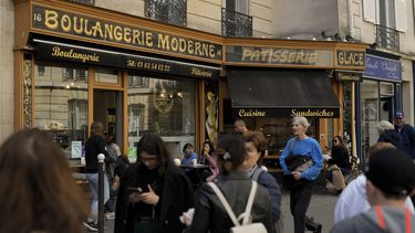 Gente camina frente a la Panadería Moderna en Place de dEstrapade, en París, el 19 de abril de 2023. El enorme éxito de la serie de Netflix Emily en Paris ha transformado una plaza tranquila de la capital francesa en un imán para turistas.