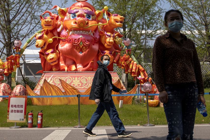 Residentes utilizan mascarillas para protegerse del coronavirus mientras caminan frente a esculturas en un parque de Wuhan, en la provincia de Hubei, en el centro de China, el jueves 9 de abril de 2020. 