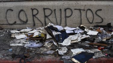 Escombros yacen frente a un grafiti el domingo 22 de noviembre de 2020 afuera del edificio del Congreso que resultó dañado durante unas protestas en la Ciudad de Guatemala