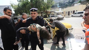 Un policía de Hamas llega con una niña herida a un hospital en Beit Lahiya, en la Franja de Gaza, el domingo 8 de octubre de 2023.&nbsp;