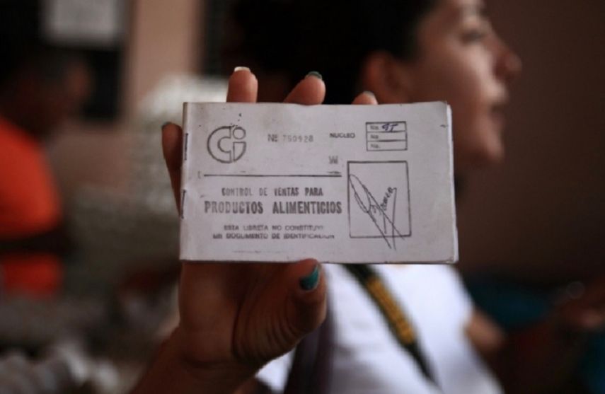 Una mujer muestra una libreta de abastecimiento.