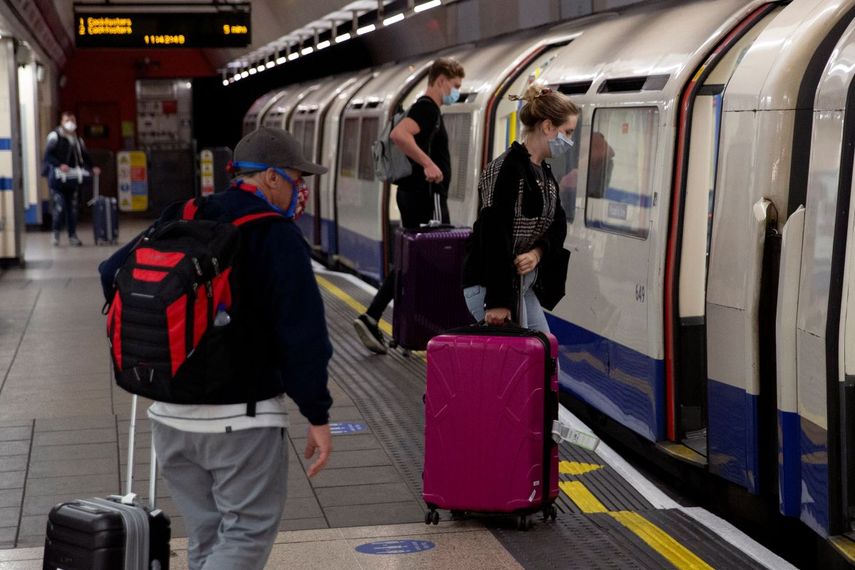 Personas con mascarillas que aterrizaron en el aeropuerto de Heathrow suben a un tren subterráneo con destino a Londres, en las terminales del metro Heathrow 2 y 3 en Londres.