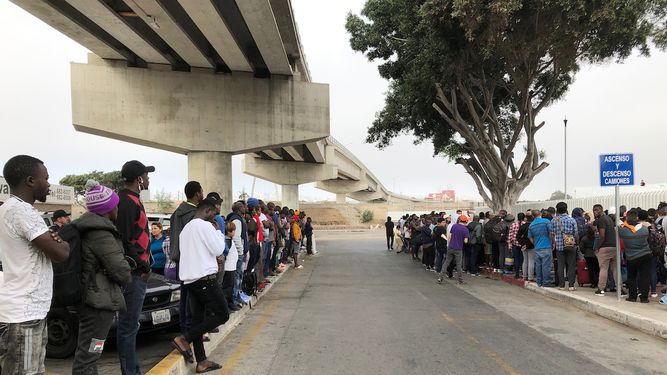 Decenas de migrantes escuchan expectantes en Tijuana, México, los nombres de quienes son llamados para que puedan iniciar una solicitud de asilo en Estados Unidos el 26 de julio del 2019.&nbsp;