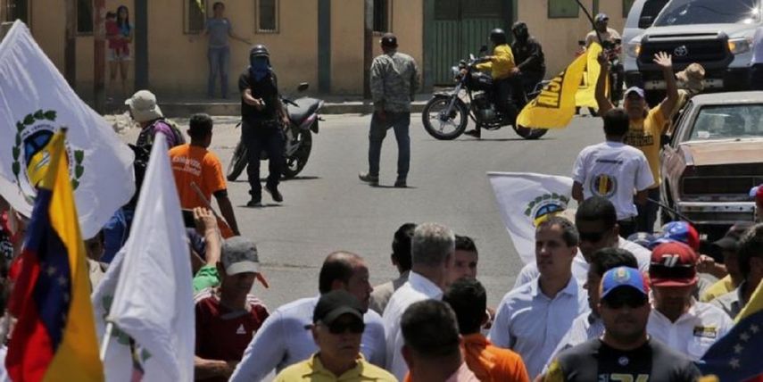 Un paramilitar del r&eacute;gimen de Nicol&aacute;s Maduro se observa apuntando con una pistola a pocos pasos del presidente encargado de Venezuela, Juan Guaid&oacute; se reun&iacute;a&nbsp;con partidarios en Barquisimeto, Venezuela.