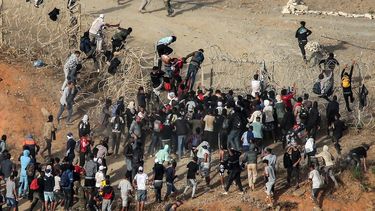 Migrantes asaltan una valla de alambre de púas mientras intentan cruzar la frontera terrestre con el enclave africano español de Ceuta, cerca de Fnideq, en el norte de Marruecos, el 15 de septiembre.