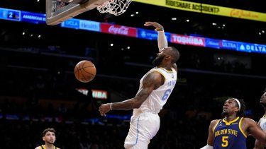 LeBron James (centro) de los Lakers de Los Ángeles clava el balón en un juego ante los Warriors de Golden State, el jueves 23 de febrero de 2023.