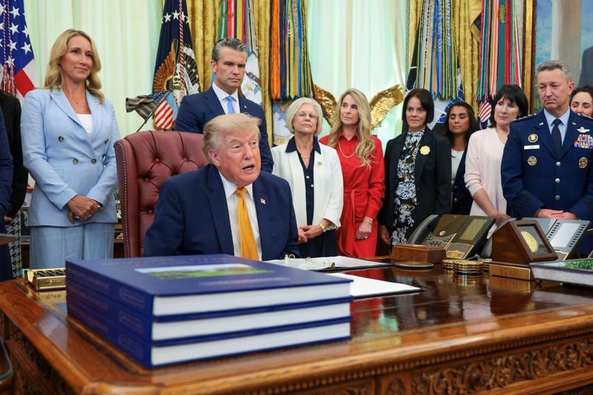 El presidente Donald Trump (sentado) se prepara para firmar una orden ejecutiva que crea la Comisión de Cónyuges Militares en el Despacho Oval de la Casa Blanca, el 3 de agosto de 2026, en Washington, DC.