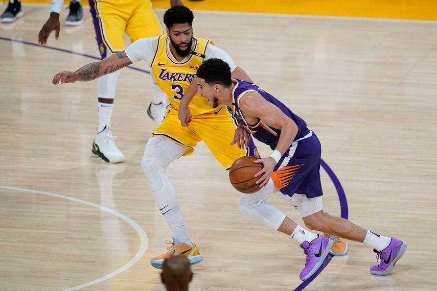 Anthony Davis (3), de los Lakers de Los Ángeles, defiende ante su rival de los Suns de Phoenix Devin Booker (1) durante el primer cuarto del Juego 6 de la primera ronda de los playoffs de la NBA