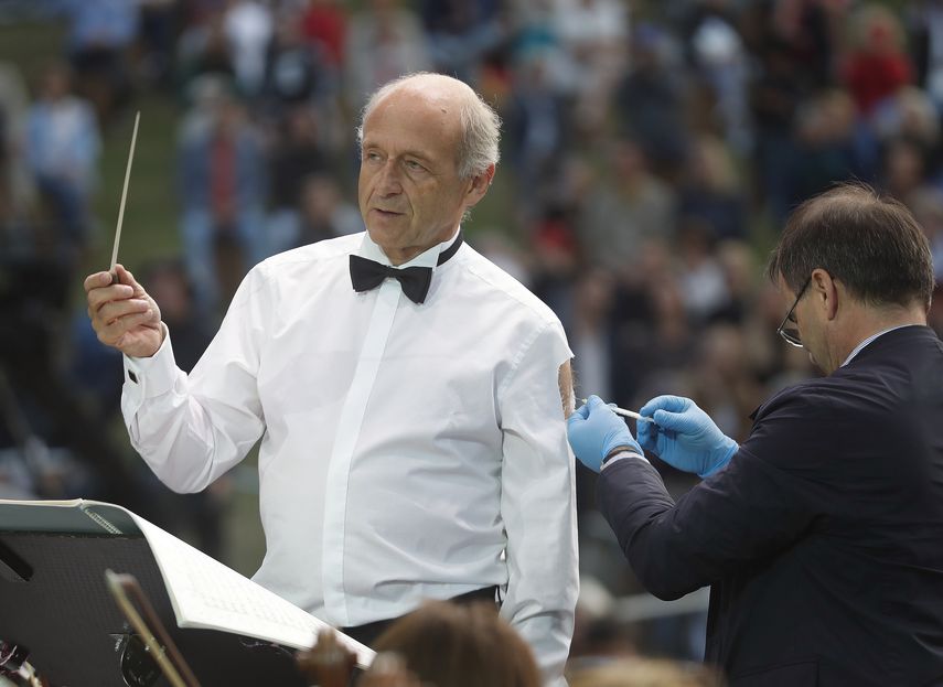 El director Ivan Fischer, fundador de la Orquesta del Festival de Budapest, recibe su tercera dosis de la vacuna contra el COVID-19 mientras dirige a la orquesta en un concierto gratuito al aire libre en Budapest, Hungría, el miércoles 25 de agosto de 2021.