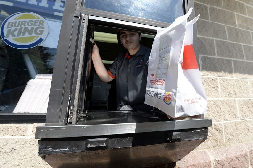 Imagen de archivo de un empleado de Burguer King que&nbsp;entrega un paquete de comida a través de una ventanilla.