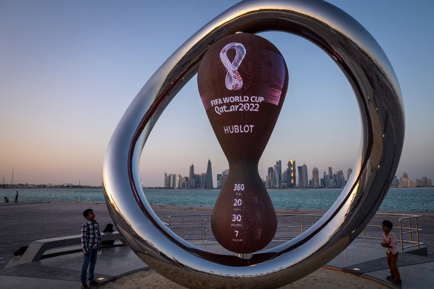 Un par de niños observa el reloj que marca la cuenta regresiva hacia el Mundial de Qatar en Doha, el 22 de noviembre de 2021