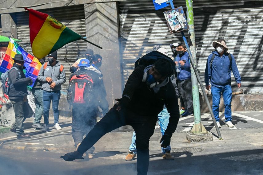 Un manifestante lanza una bandera nacional contra la policía antidisturbios durante una protesta en La Paz, el 18 de mayo de 2026, para exigir la renuncia del presidente de Bolivia, Rodrigo Paz.