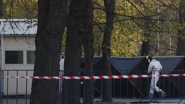 Un agente, con un equipo de protección, cubre el lugar donde un auto impactó contra la cerca de acceso a la embajada de Rusia, en Bucarest, Rumanía, el 6 de abril de 2022.&nbsp;