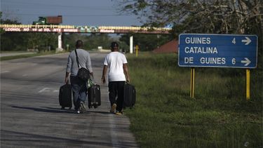 Personas con maletas caminan por una carretera en busca de un autobús o un taxi en Catalina de Güines, Cuba.