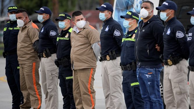 Integrantes de la guerrilla del ELN Yamit Picon (L-2) y Henry Trigos (L-5), y Alexander Montoya Usuga (R-2), integrante de la banda narcotraficante Clan del Golfo, son escoltados por policías y agentes de la Interpol antes su extradición a Estados Unidos, en la Base Antinarcóticos de la Policía Nacional en Bogotá, el 19 de agosto de 2021.
