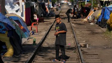 Un niño migrante venezolano juega en las vías del tren bordeadas de tiendas de campaña y refugios improvisados en Ciudad de México.