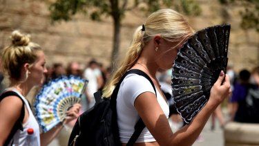 Dos mujeres usan abanico de manos para mitigar el calor abrasador que afecta el país, en Sevilla, España.