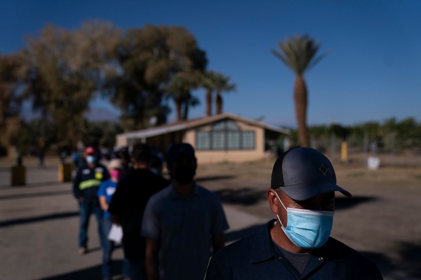 Jornaleros agrícolas hispanos hacen fila para recibir la vacuna de Pfizer-BioNTech contra el COVID-19 el jueves 21 de enero de 2021, en Mecca, California.