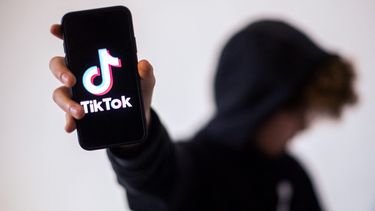 En esta fotografía, una adolescente posa presentando un teléfono inteligente con el logo de la red social TikTok.