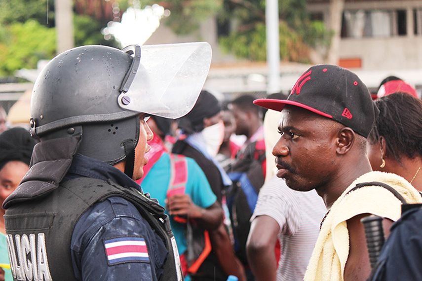 Un migrante africano habla con un policía de Costa Rica, en la frontera con Panamá. (EFE)
