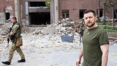 Esta fotografía tomada y publicada por el servicio de prensa de la presidencia ucraniana el 18 de junio de 2022 muestra al presidente ucraniano Volodímir Zelenski (derecha) caminando frente a un edificio parcialmente destruido durante su visita a la posición de las tropas ucranianas en la región de Mykolaiv. &nbsp;