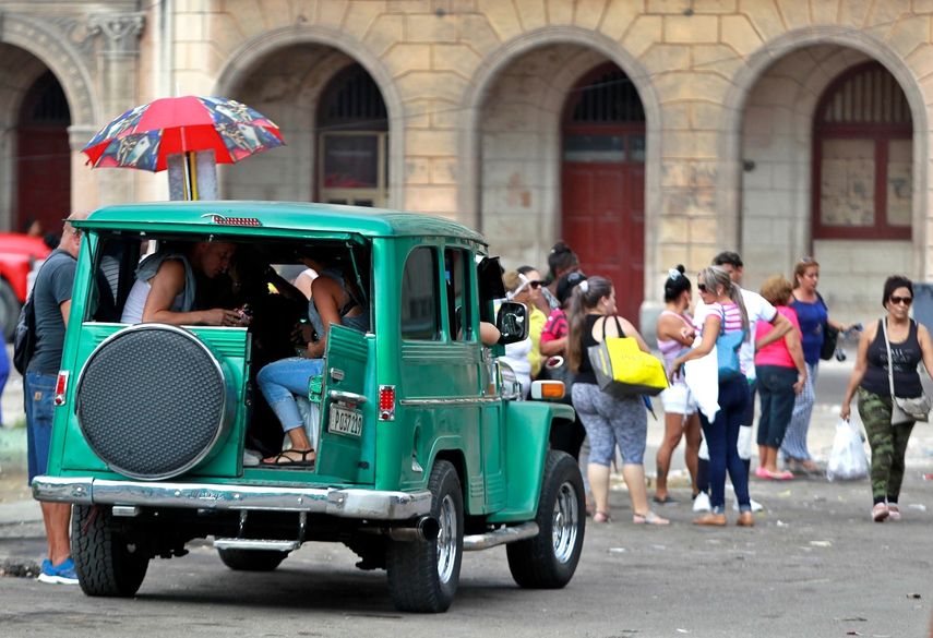 Varias personas esperan a que se complete la cantidad de pasajeros de un taxi particular en las inmediaciones de la terminal de ómnibus en La Habana, Cuba.