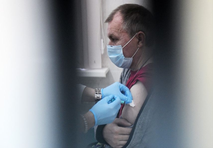 Un trabajador de la salud administra a un hombre una dosis de la vacuna rusa Sputnik V (Gam-COVID-Vac) contra el COVID-19 en un centro de vacunación en San Petersburgo, el 21 de febrero de 2021, mientras Rusia lanzaba un COVID-19 masivo. Campaña de vacunación para personas sin hogar.