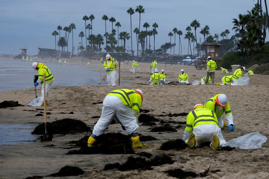 Trabajadores en trajes de protección limpian una playa contaminada de Corona del Mar, en el sur de California, el 7 de octubre de 2021.