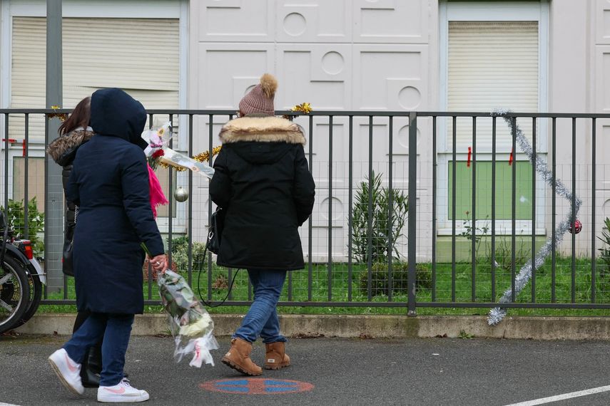 La gente lleva ramos de flores al piso donde se descubrieron los cuerpos de una mujer y sus cuatro hijos, en Meaux, al este de París, el 26 de diciembre de 2023.