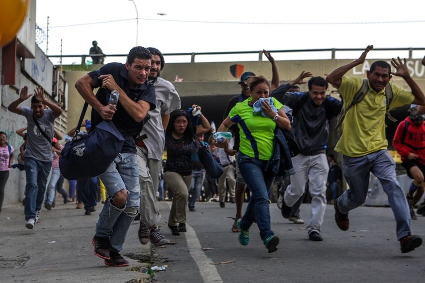 Un grupo de venezolanos huye de la represión de los agentes de seguridad del régimen de Nicolás Maduro durante una protesta opositora en Caracas.