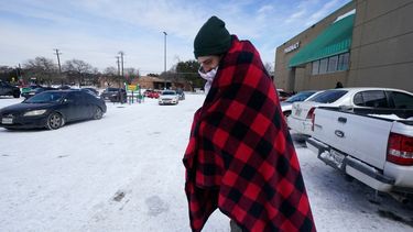 Cody Jennings utiliza un cobertor para mantenerse caliente afuera de una tienda en Dallas, el martes 16 de febrero de 2021.