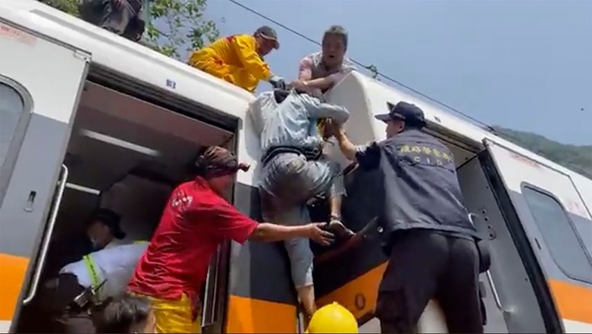 En esta imagen tomada de un video publicado por hsnews.com.tw, un pasajero (centro) recibe ayuda para subir encima de un tren descarrilado en la región de Hualien, en el este de Taiwán, el 2 de abril de 2021.&nbsp;