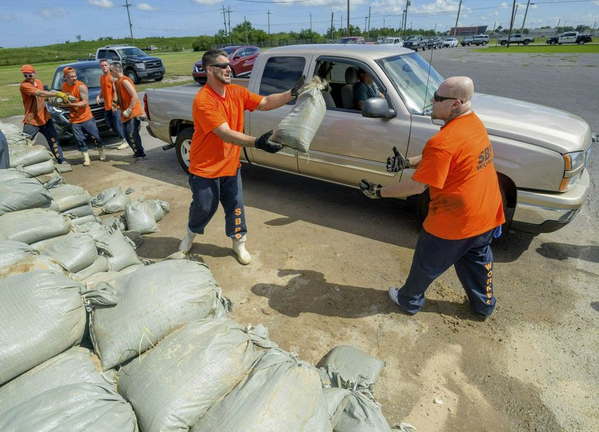 Presos de la comisaría de la parroquia St. Bernard entregan bolsas de arena a los residentes de Chalmette, Luisiana, 11 de julio de 2019, a la espera de la tormenta tropical Barry.&nbsp;