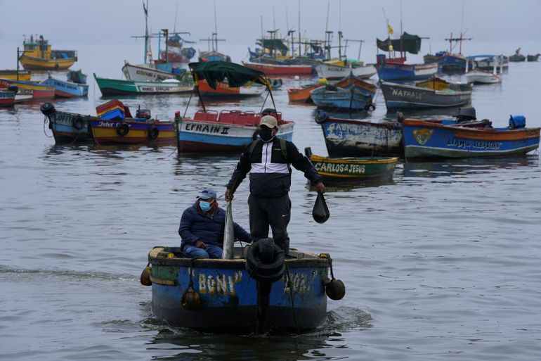 El pescador Máximo Castro apunta hacia el sur, la dirección de donde provino el derrame de petróleo, en su bote en la contaminada bahía de Ancón en Lima, Perú, el viernes 21 de enero de 2022.