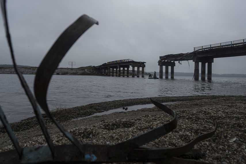 Hombres llevan ayuda humanitaria en una barca a través del río Siverskyi-Donets, frente a un puente destrozado en Staryi-Saltiv, Ucrania, el 27 de septiembre de 2022.&nbsp;