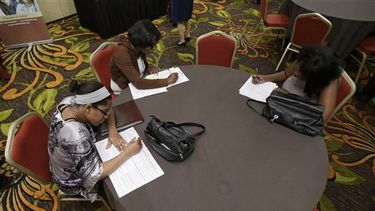 Desirae Gooch, a la izquierda, llena una solicitud para empleo de ayudante de enfermera con otras personas que hacen lo mismo en la Feria de Carreras de Cleveland en Independence, Ohio, el jueves 12 de junio de 2014. Las empresas de Estados Unidos anun