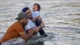 Migrantes cruzan el río Bravo con una infante en brazos para llegar a Estados Unidos. 