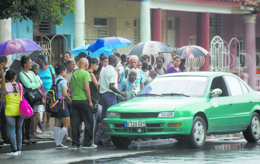 Habaneros esperan por abordar taxis&nbsp;bajo la lluvia.