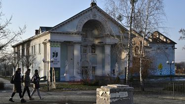 La gente pasa frente a una casa de la cultura muy dañada en Irpin, al noroeste de Kyiv, el 23 de diciembre de 2022, en medio de la invasión rusa de Ucrania. El edificio de la biblioteca salió prácticamente indemne de los intensos combates de la guerra.
